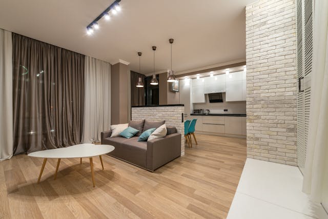 Furnished living room with a table, couch, and a half wall exposing the kitchen behind it